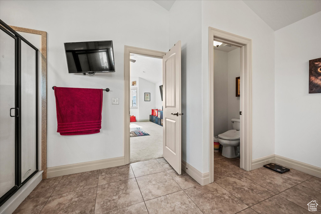 Bathroom featuring walk in shower, lofted ceiling, tile patterned floors, and toilet