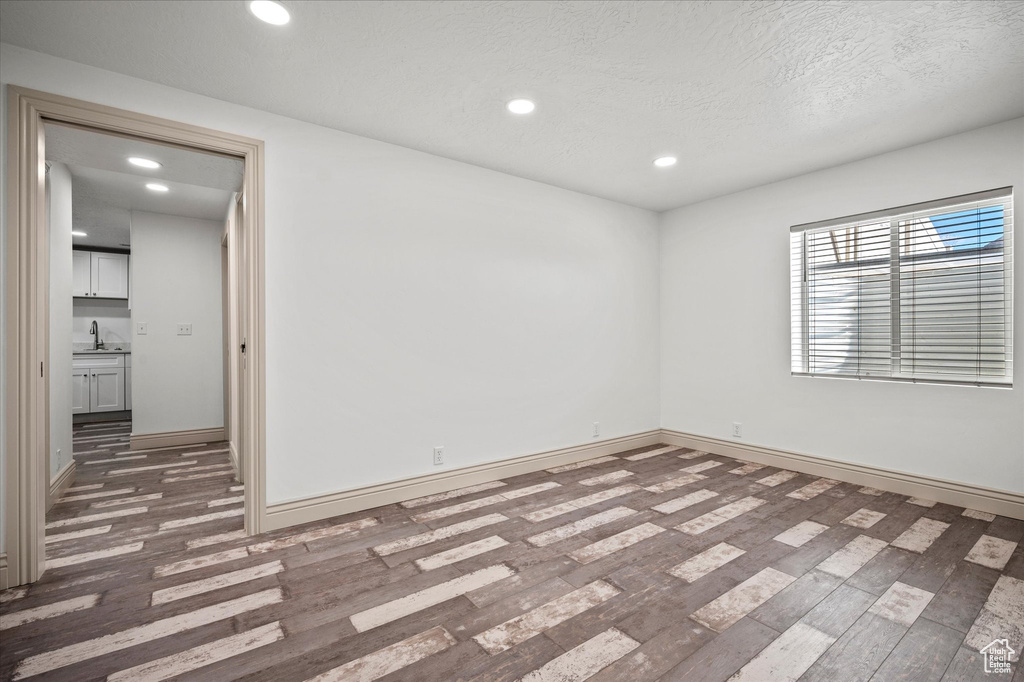 Unfurnished room featuring sink, dark hardwood / wood-style floors, and a textured ceiling