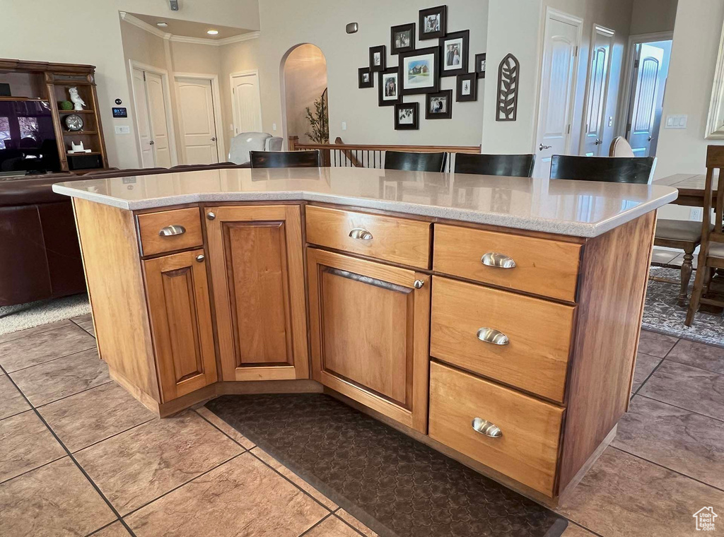 Kitchen with crown molding, a center island, a breakfast bar area, and light tile patterned floors
