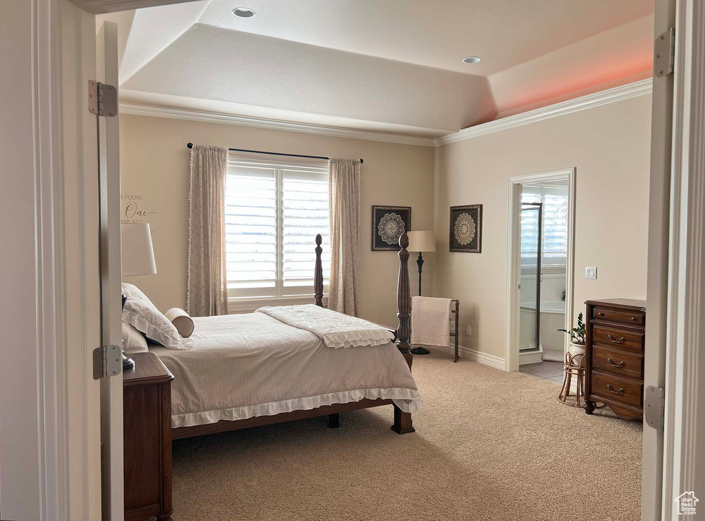 Carpeted bedroom with a raised ceiling, ornamental molding, lofted ceiling, and ensuite bath