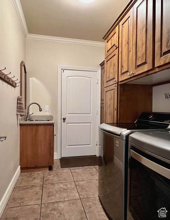 Laundry area with sink, light tile patterned floors, washing machine and dryer, cabinets, and ornamental molding