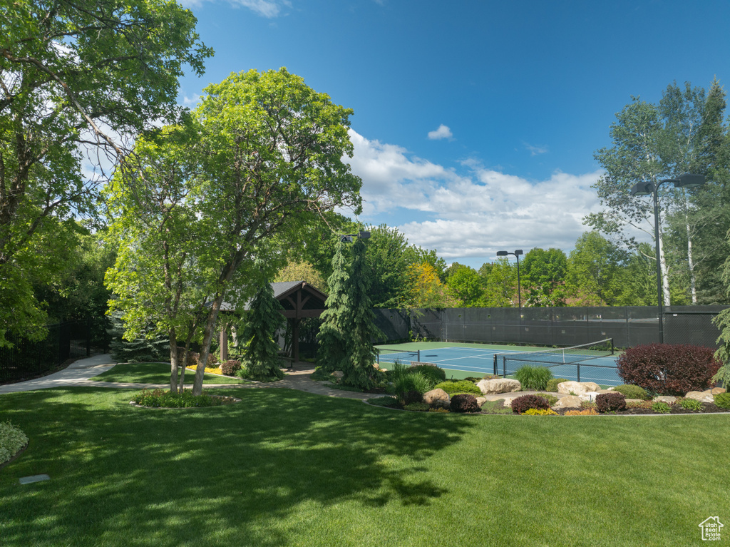 View of tennis court with view of wooded area