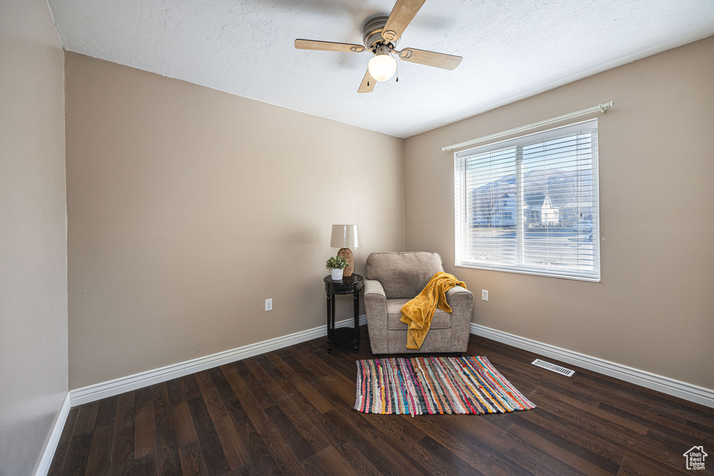 Living area featuring dark wood-type flooring, ceiling fan, and a textured ceiling