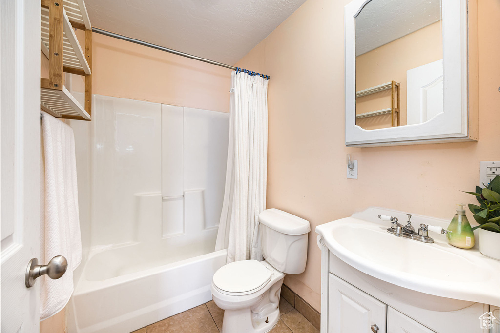 Full bathroom with tile patterned flooring, vanity, shower / tub combo, and toilet