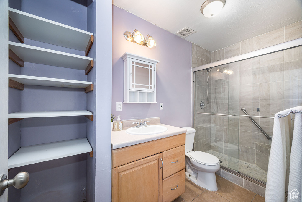 Bathroom with tile patterned flooring, vanity, toilet, and walk in shower