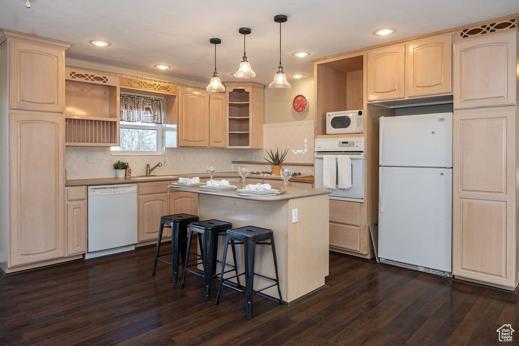 Kitchen with sink, white appliances, dark hardwood / wood-style floors, a kitchen island, and light brown cabinets