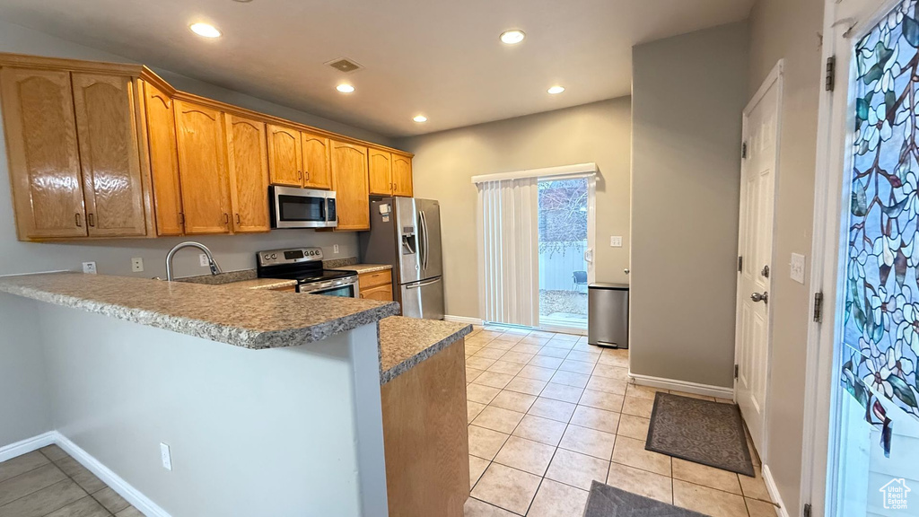 Kitchen with stainless steel appliances, sink, light tile patterned floors, and kitchen peninsula