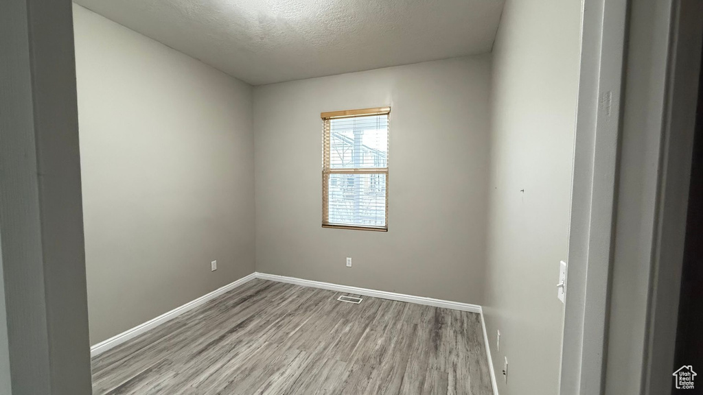 Spare room with a textured ceiling and light wood-type flooring