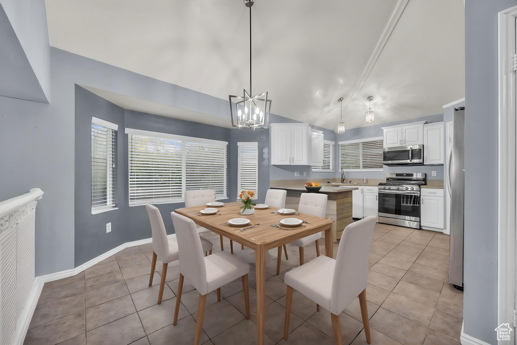 Dining area with baseboards, a chandelier, light tile patterned floors, and lofted ceiling