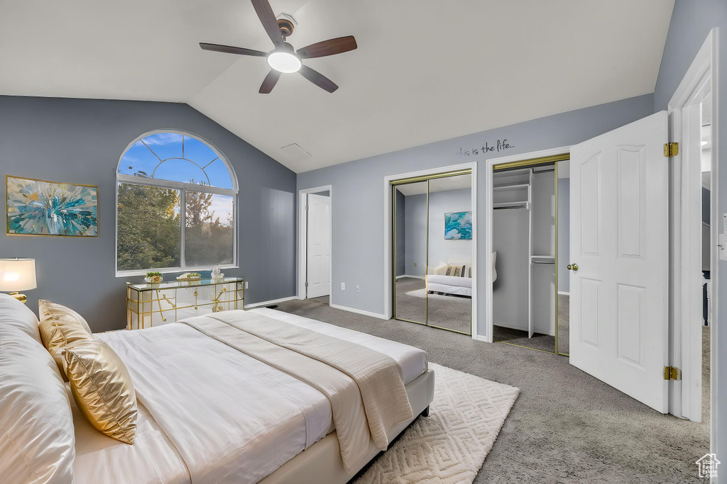 Bedroom featuring ceiling fan, carpet floors, two closets, baseboards, and vaulted ceiling
