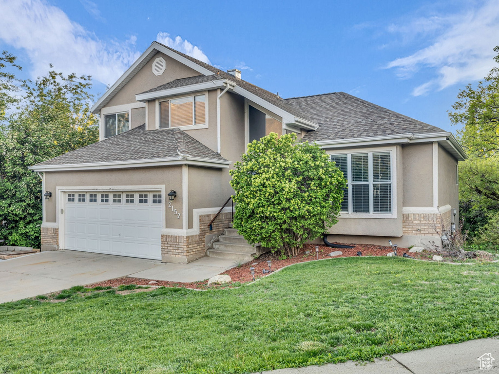 View of front of home with an attached garage, driveway, roof with shingles, and stucco siding