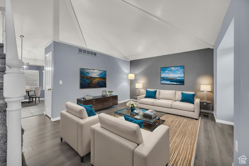 Living room featuring baseboards, visible vents, wood finished floors, and high vaulted ceiling