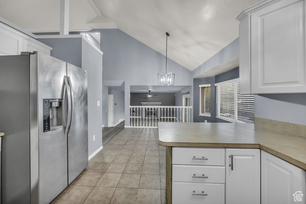 Kitchen with a peninsula, decorative light fixtures, white cabinetry, and stainless steel fridge with ice dispenser