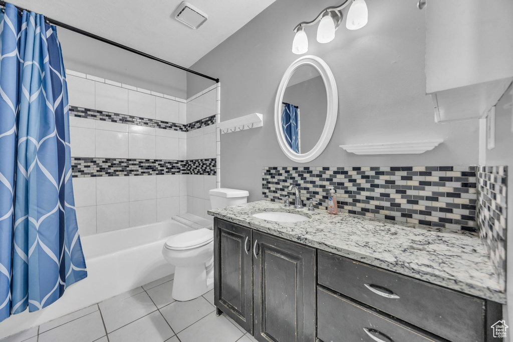 Bathroom with vanity, shower / tub combo with curtain, toilet, tile patterned floors, and tasteful backsplash