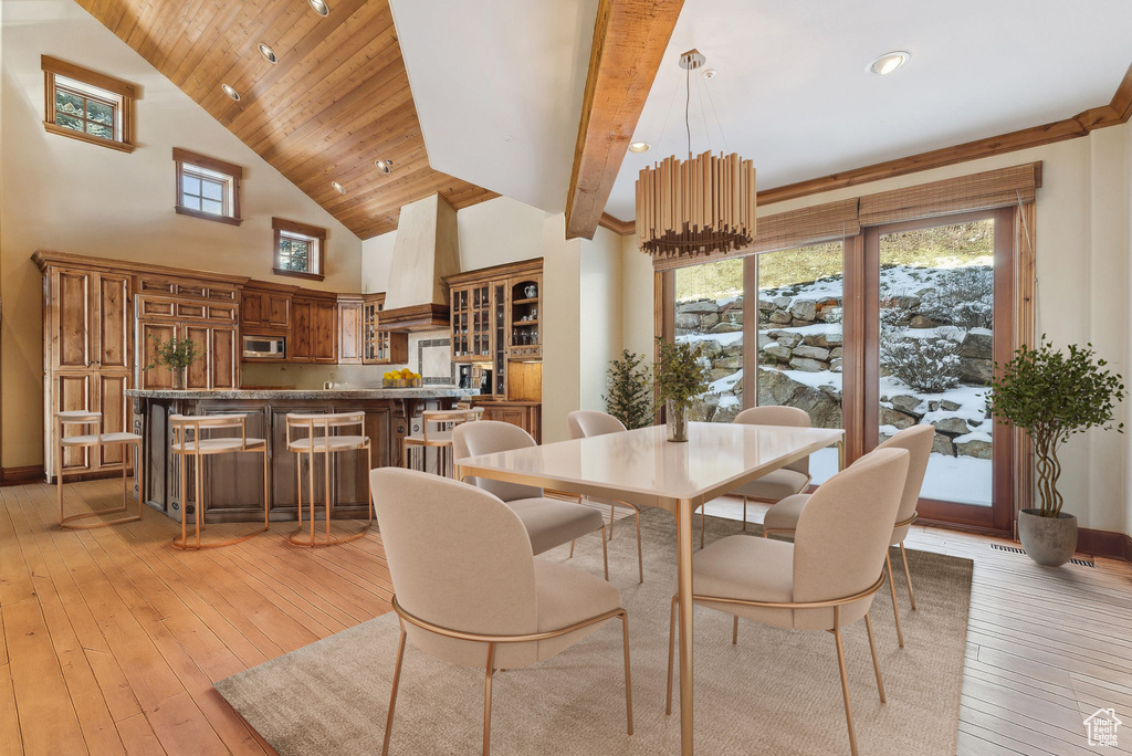 Dining area with light wood-style flooring and high vaulted ceiling