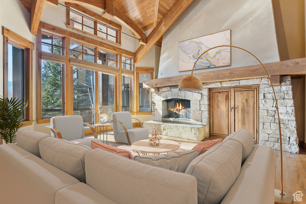Living room with a wooden ceiling with exposed beams, high vaulted ceiling, hardwood / wood-style floors, and a fireplace