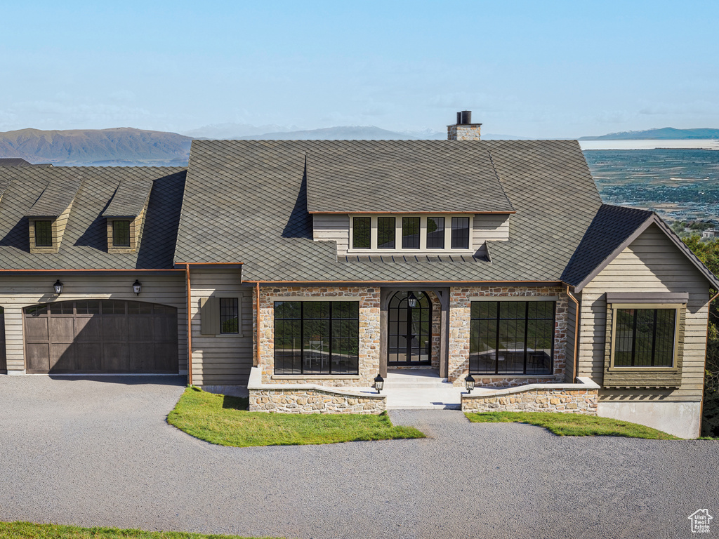 View of front facade featuring a mountain view, driveway, an attached garage, and a chimney