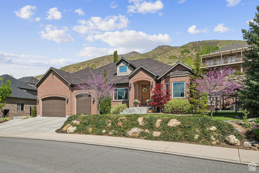 View of front of home featuring concrete driveway, brick siding, an attached garage, and a mountain view