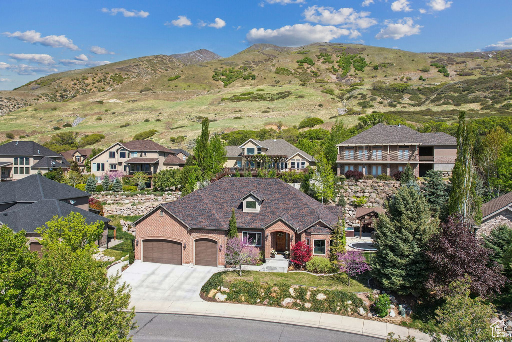 View of front of property featuring a residential view, a mountain view, concrete driveway, and a garage