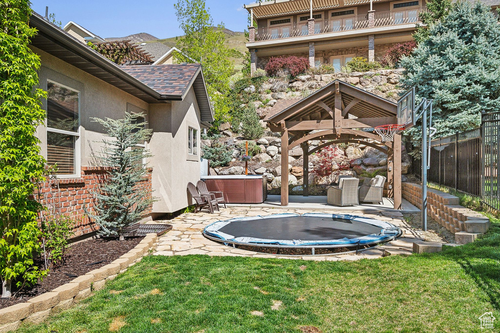 View of yard featuring fence, a gazebo, a hot tub, and a patio area