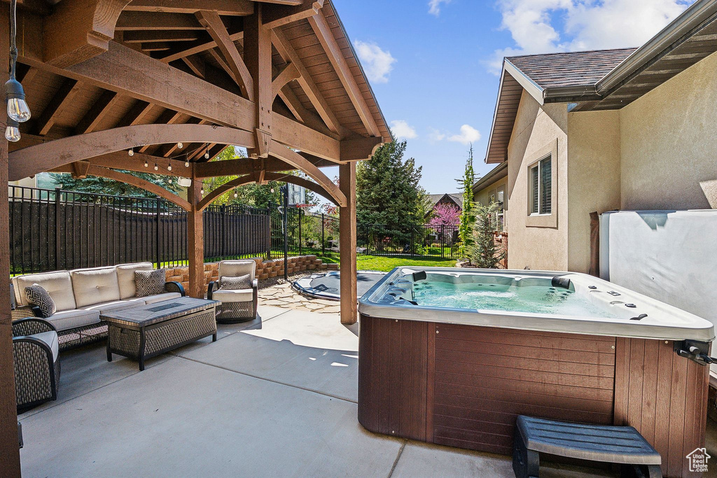 View of patio featuring outdoor lounge area, fence, a grill, a gazebo, and a hot tub