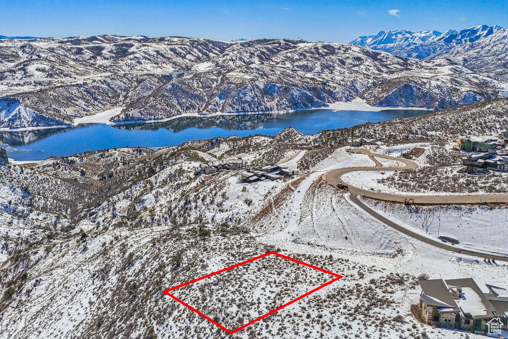 Snowy aerial view with a water and mountain view and property boundaries highlighted