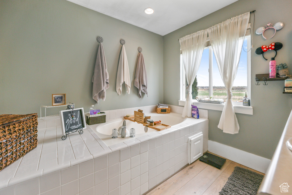 Full bath with baseboards, a garden tub, and wood finished floors