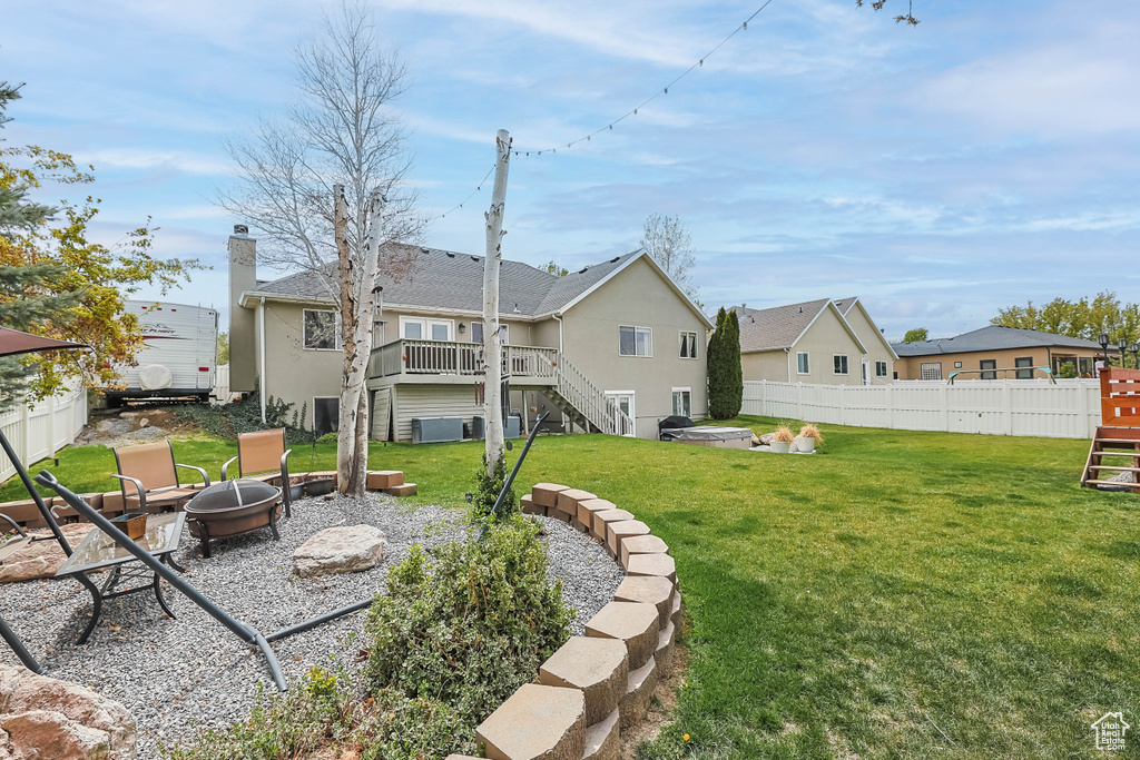 Rear view of property featuring stairway, a lawn, an outdoor fire pit, fence, and a wooden deck
