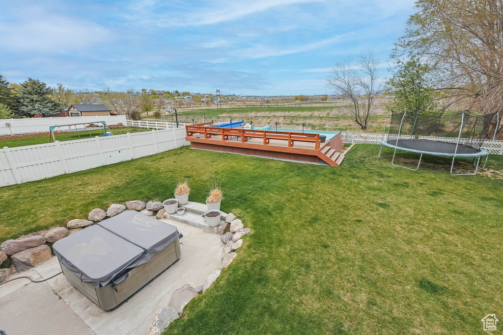 View of yard featuring a wooden deck, a trampoline, and a fenced backyard