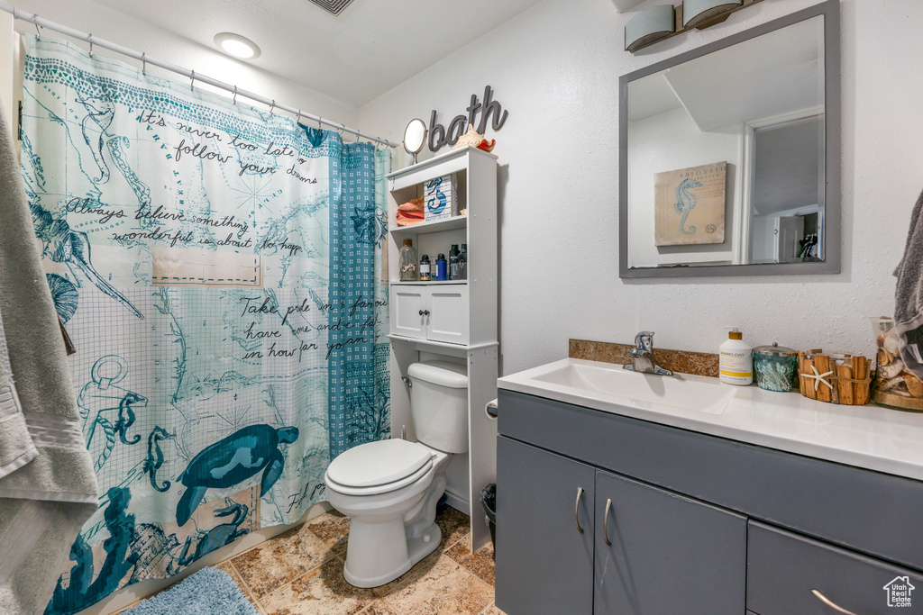 Bathroom featuring toilet, vanity, a shower with shower curtain, and visible vents