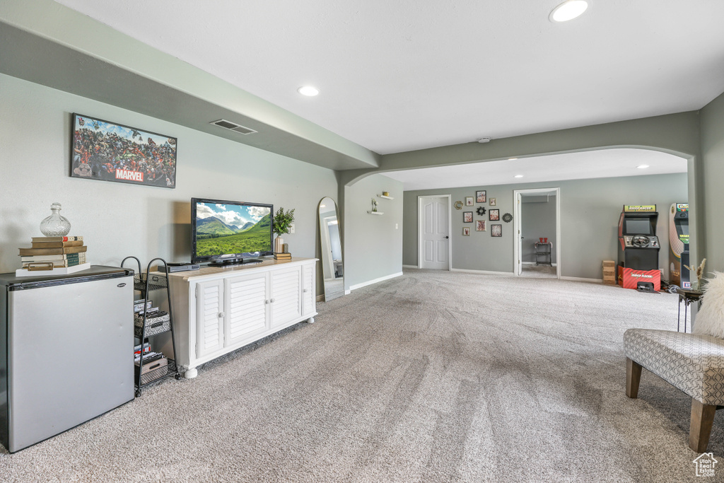 Carpeted living area featuring baseboards, arched walkways, visible vents, and recessed lighting