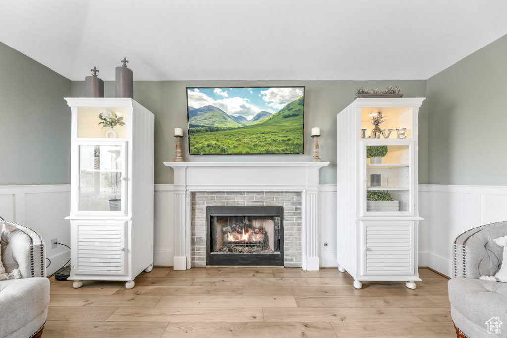 Living room featuring wainscoting, a lit fireplace, and wood finished floors