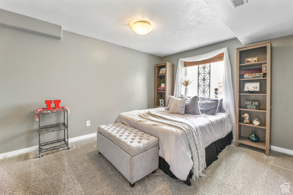 Bedroom featuring carpet flooring, an AC wall unit, baseboards, and visible vents