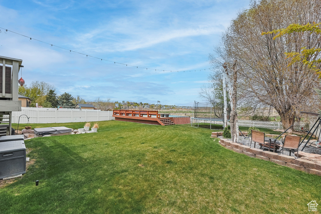 View of yard with a trampoline, a patio, a fenced backyard, and a deck