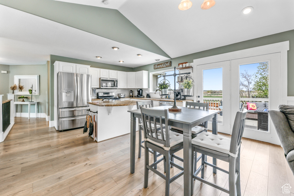 Dining space featuring recessed lighting, vaulted ceiling, and light wood-style flooring