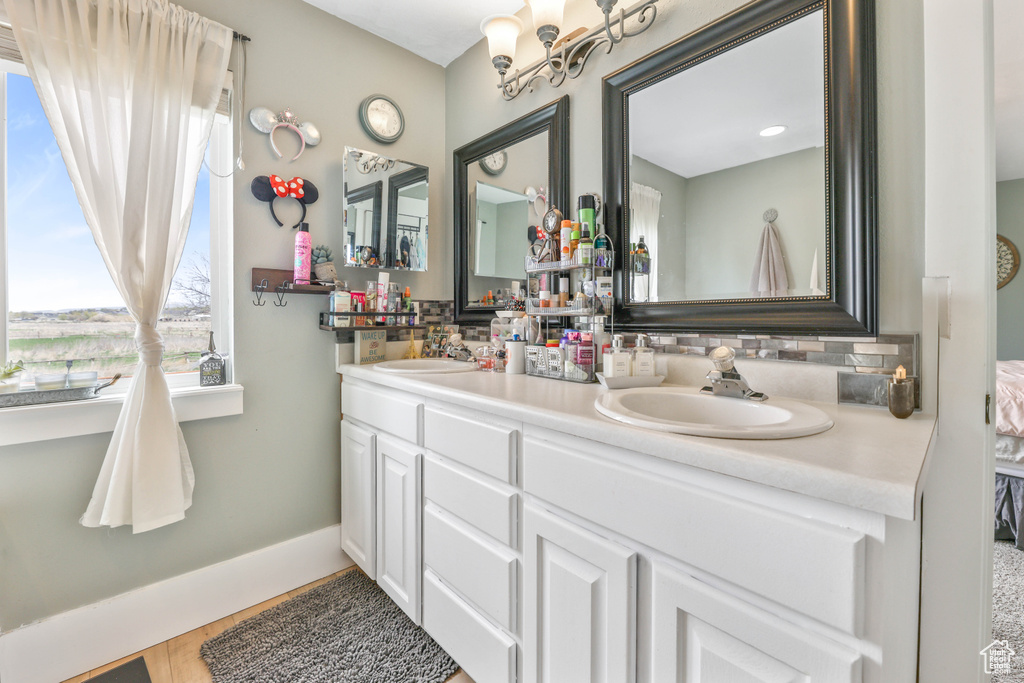 Bathroom featuring decorative backsplash, baseboards, a sink, and double vanity