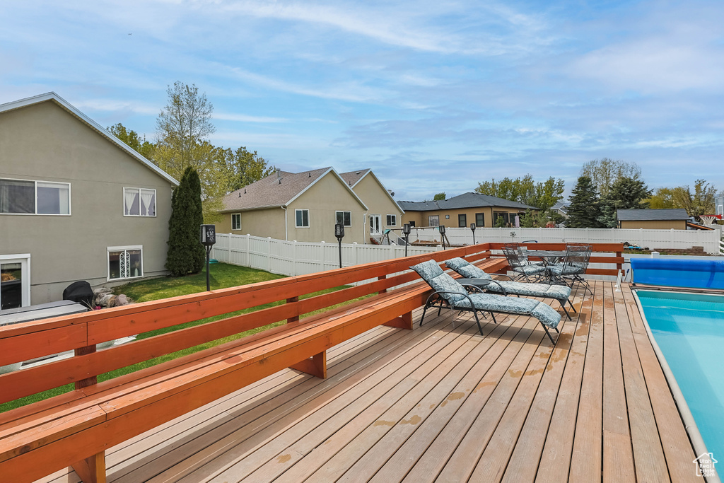 Wooden deck featuring a lawn, a fenced backyard, a fenced in pool, and a residential view