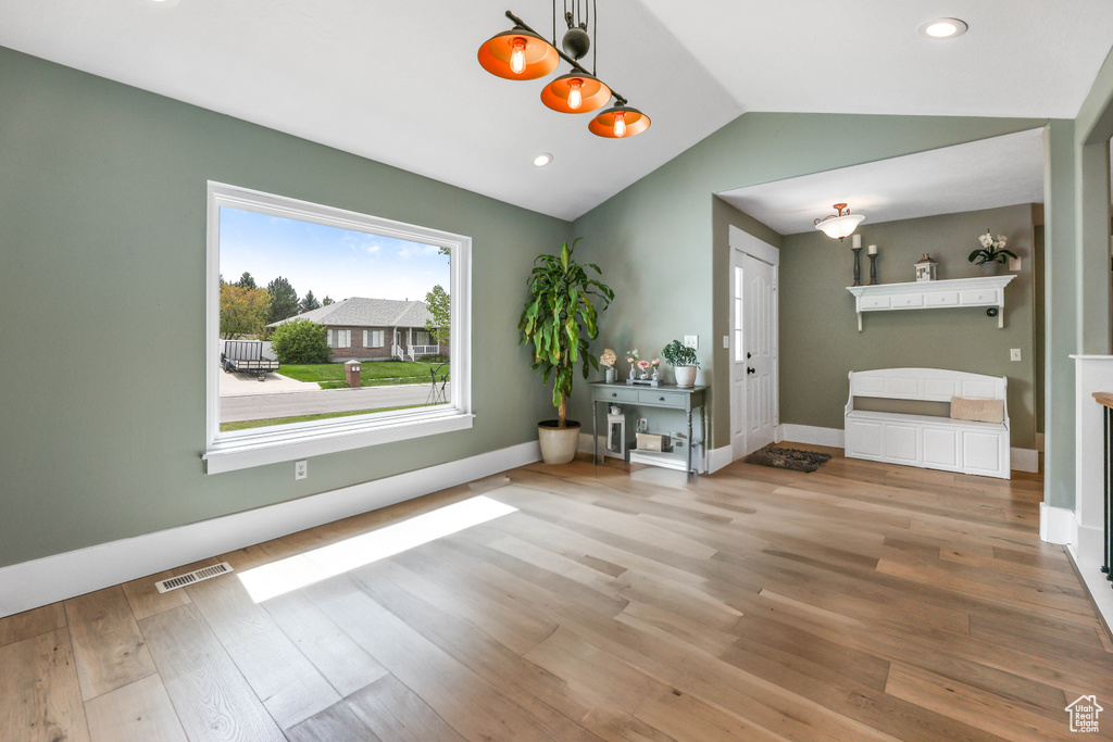 Interior space featuring vaulted ceiling, wood finished floors, visible vents, and baseboards