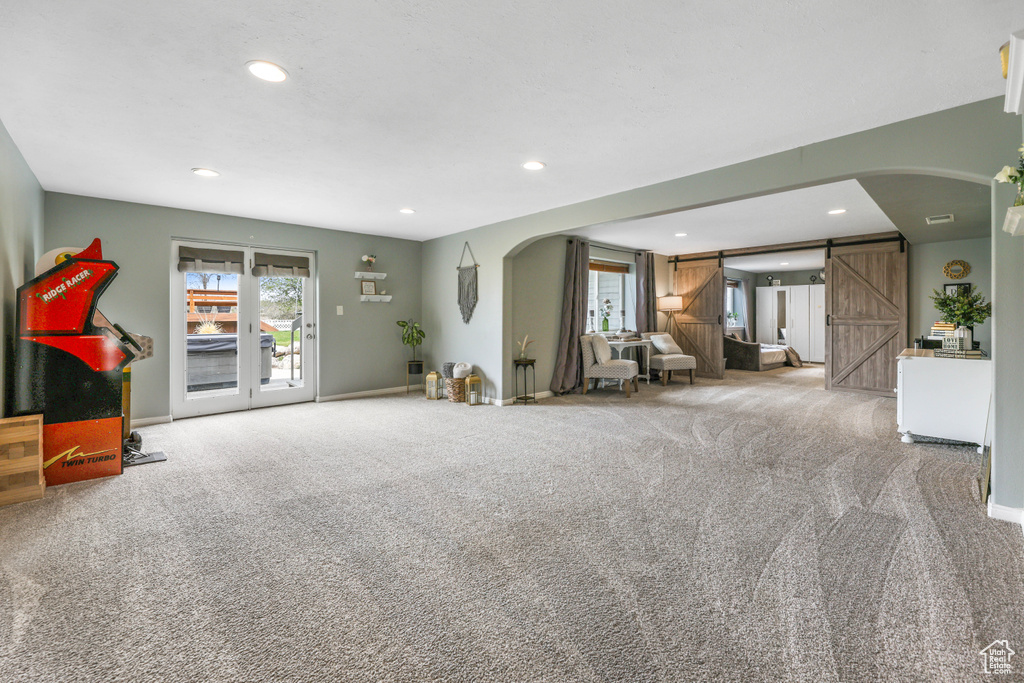Living area featuring arched walkways, carpet, recessed lighting, and a barn door