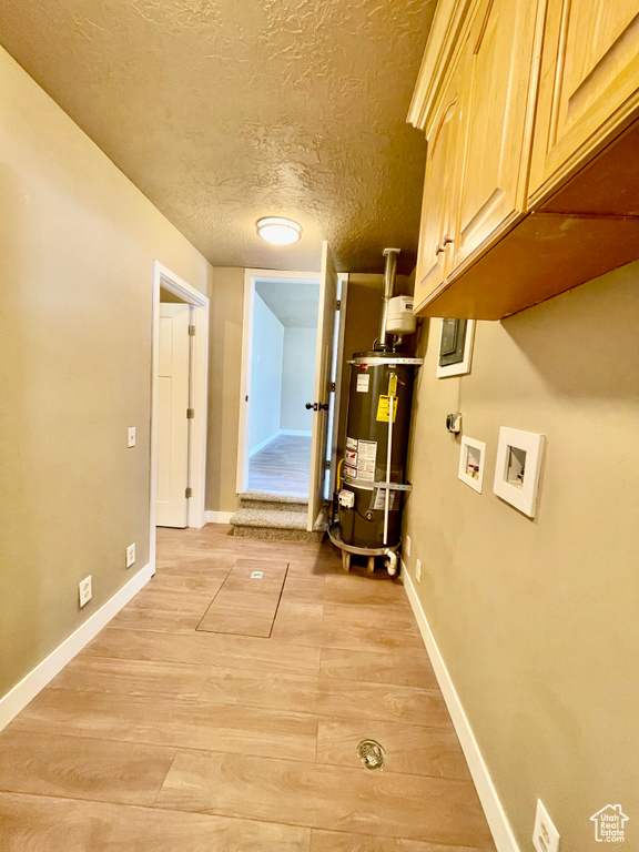 Corridor with light hardwood / wood-style floors, a textured ceiling, and gas water heater