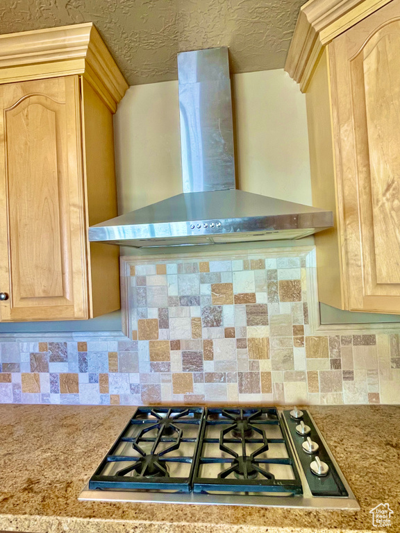 Kitchen featuring gas stovetop, wall chimney range hood, and light brown cabinetry