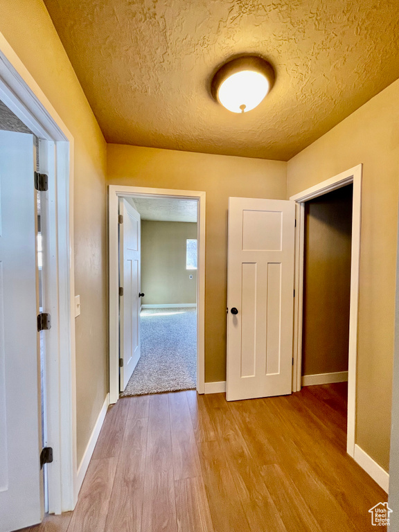 Corridor featuring light hardwood / wood-style flooring and a textured ceiling