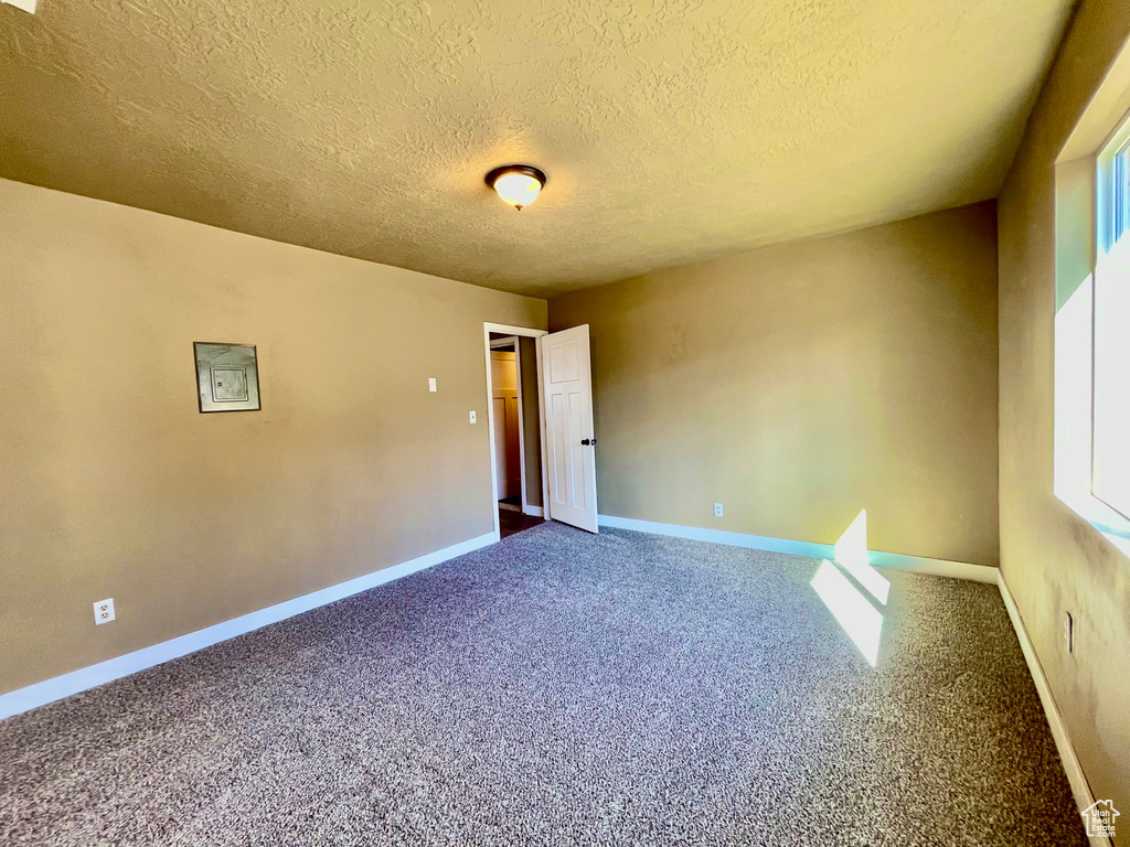 Carpeted empty room with a textured ceiling