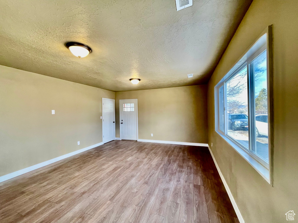 Empty room featuring a textured ceiling and light wood-type flooring