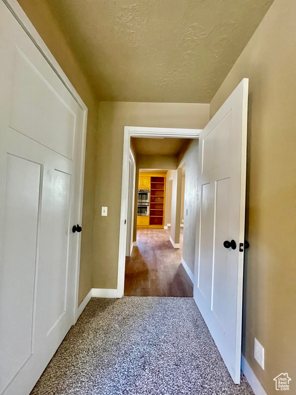 Corridor with carpet floors and a textured ceiling