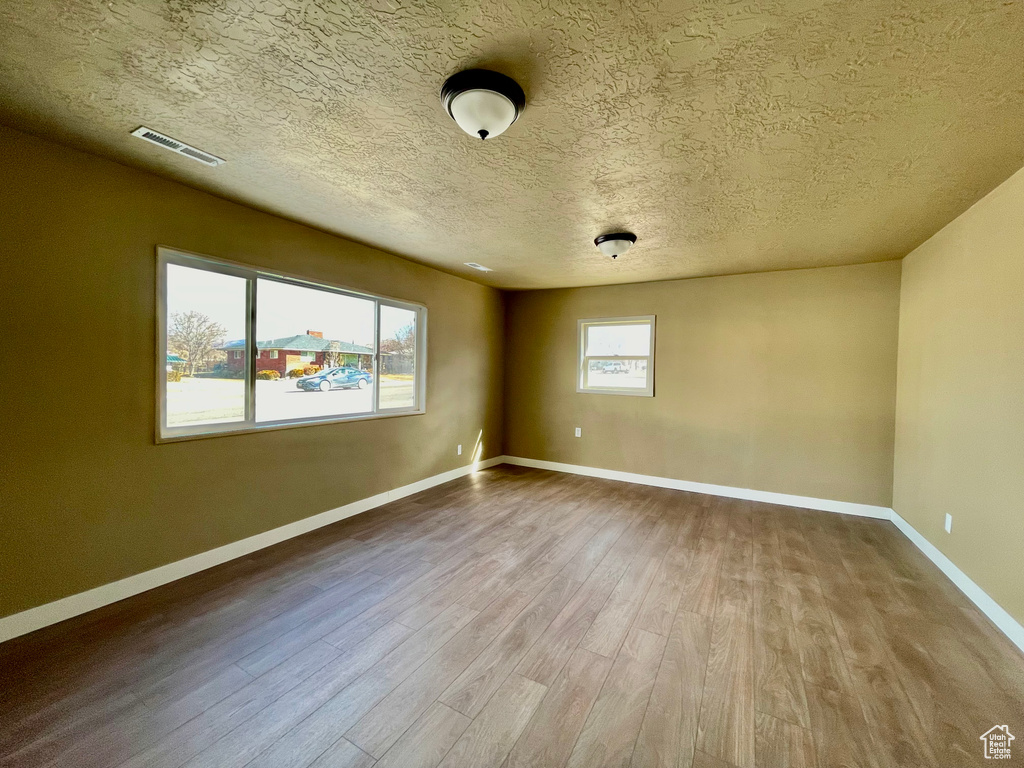 Spare room featuring wood-type flooring and a textured ceiling