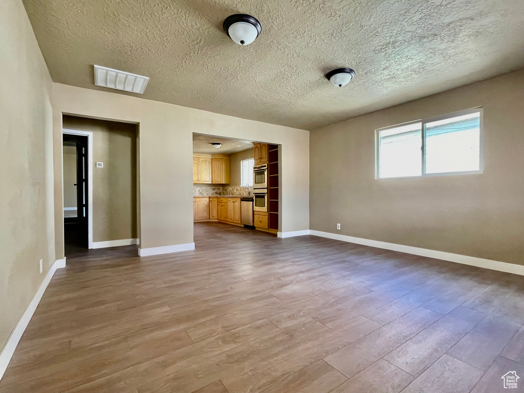 Unfurnished living room with a textured ceiling and light hardwood / wood-style floors