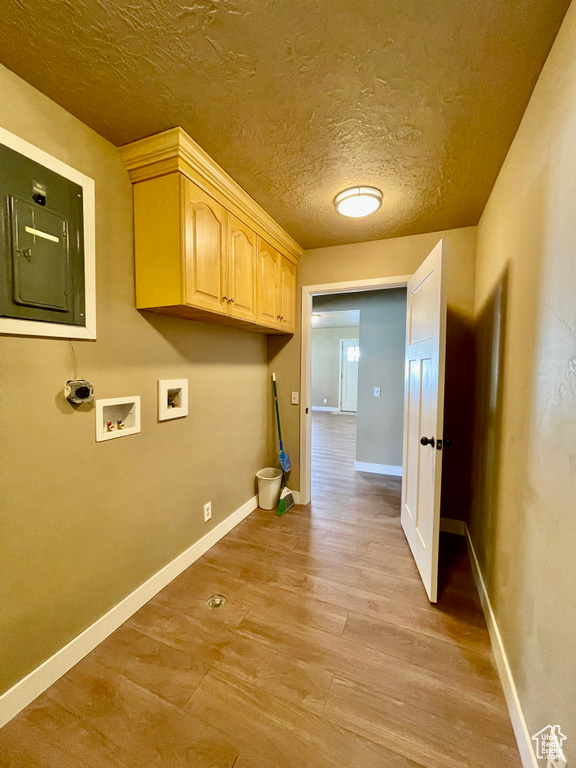 Washroom with cabinets, washer hookup, a textured ceiling, and light hardwood / wood-style floors