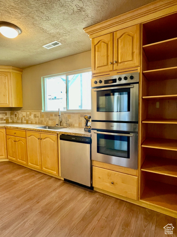 Kitchen featuring stainless steel appliances, tasteful backsplash, sink, and light hardwood / wood-style flooring