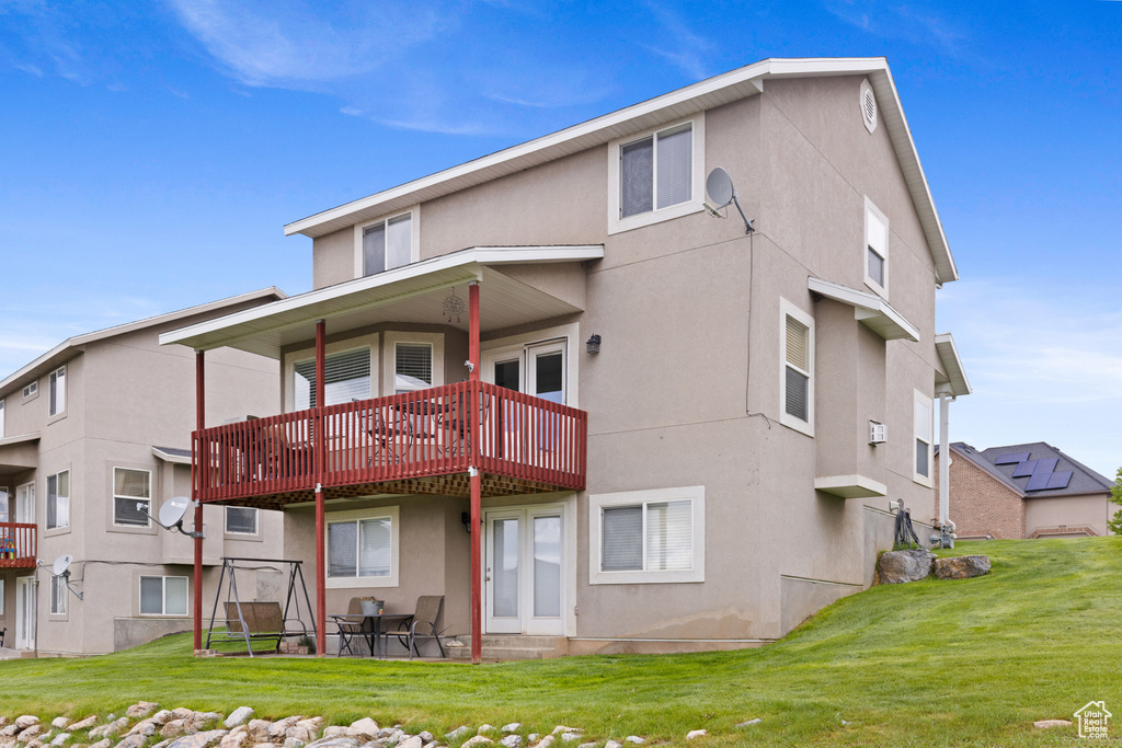 Rear view of property featuring stucco siding, a lawn, and a patio area